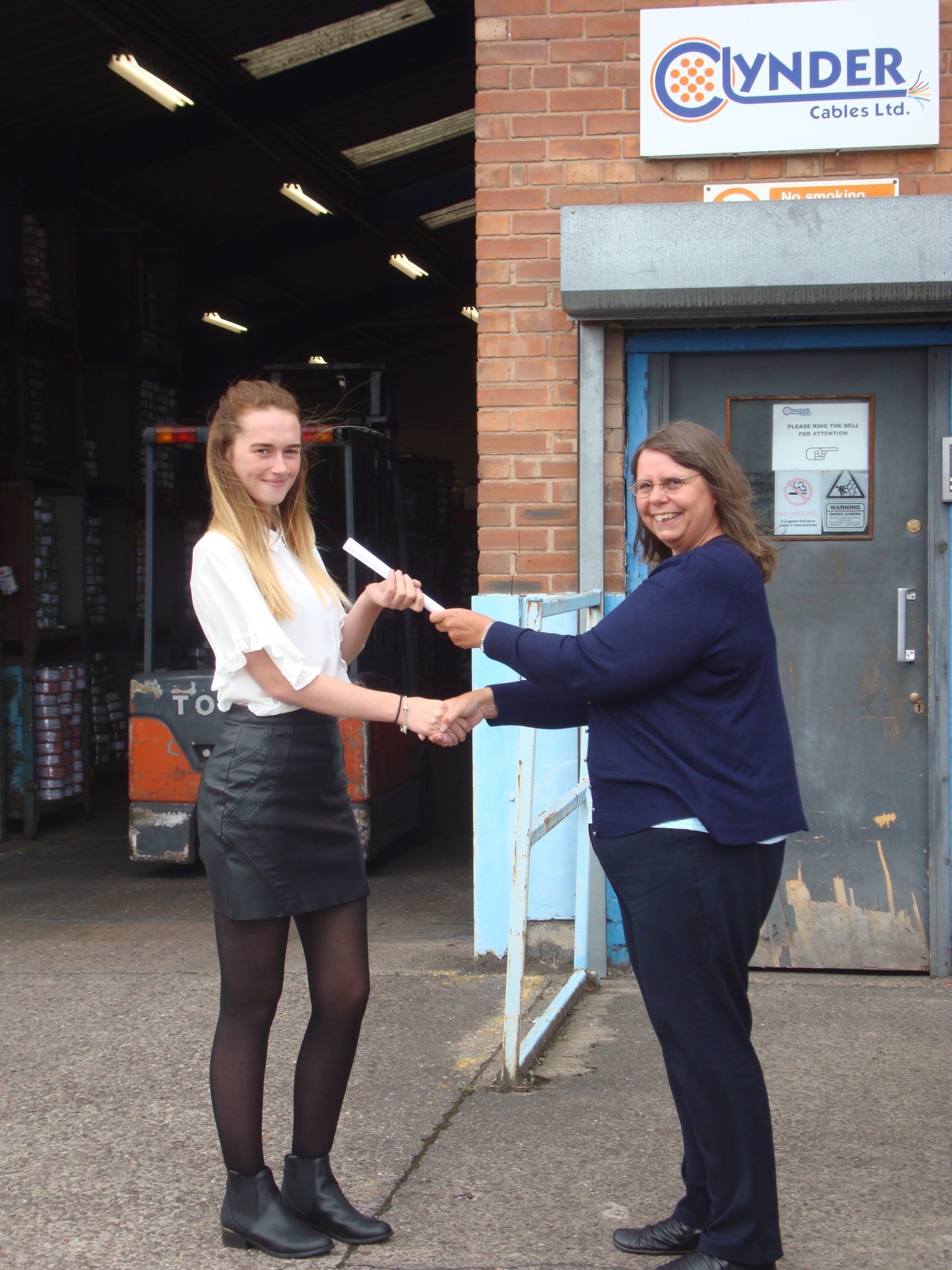 a manager handing a sales assistant a certificate in front of the clynder cables warehouse